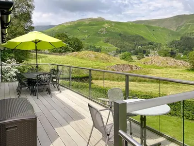 a balcony with a table and chairs and an umbrella at Le Tholonet in Grasmere