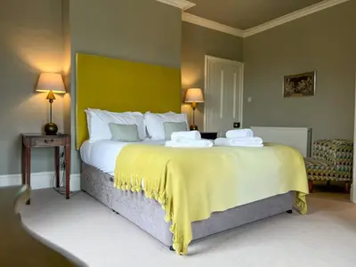 a bedroom with a large bed with a yellow wall at High House Cottage, Southwaite in a rural setting with garden, BBQ & hot tub in Southwaite