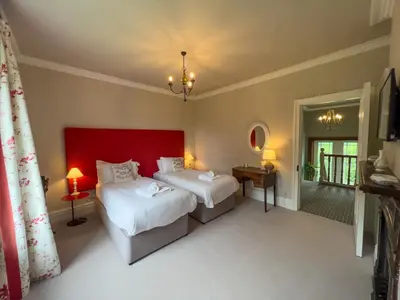 a bedroom with two beds and a red headboard at High House Cottage, Southwaite in a rural setting with garden, BBQ & hot tub in Southwaite