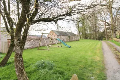 a playground with a swing in a yard at High House Cottage, Southwaite in a rural setting with garden, BBQ & hot tub in Southwaite
