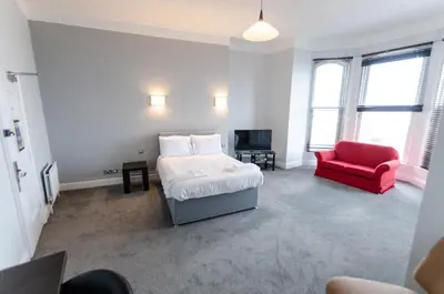 a bedroom with a bed and a red chair at Opul Boutique at Admiral House in Douglas