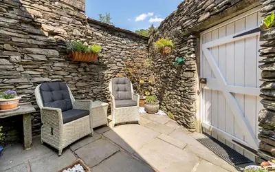 two chairs sitting on a patio next to a garage at Poet's Corner in Grasmere