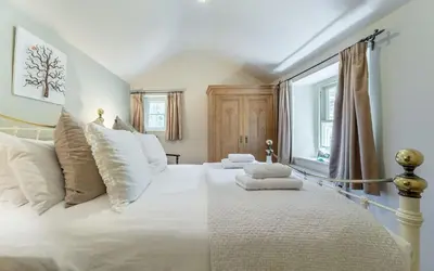 a bedroom with a large white bed with white pillows at Poet's Corner in Grasmere