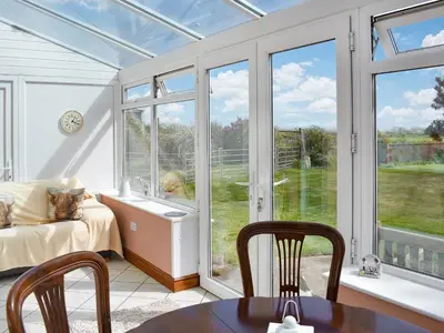 a conservatory with a room with a bed and a window at The Stables in Beckfoot