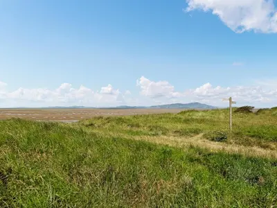 a field with green grass and a dirt road at The Stables in Beckfoot