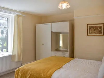 a bedroom with a bed and a cabinet and a window at The Stables in Beckfoot
