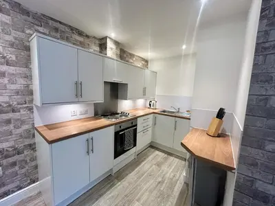 a kitchen with white cabinets and a brick wall at Central apartments in Carlisle