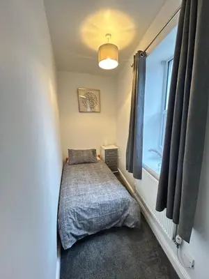 a small bedroom with a bed and a window at Central apartments in Carlisle