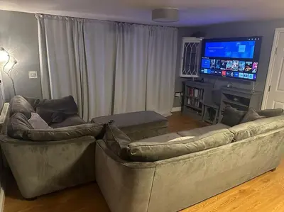 a living room with two couches and a flat screen tv at The hot tub by the waterfall - facilities included in Lower Foxdale