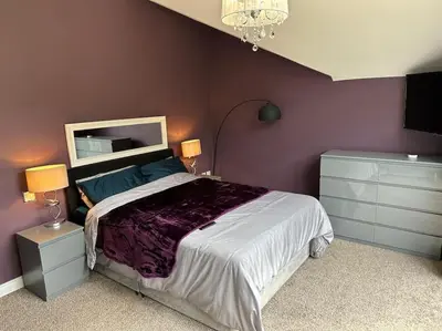 a bedroom with a large bed and purple walls at The hot tub by the waterfall - facilities included in Lower Foxdale