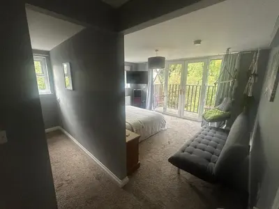 a bedroom with a bed and a couch and a window at The hot tub by the waterfall - facilities included in Lower Foxdale
