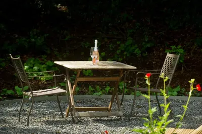 a wooden table with two chairs and a bottle on it at Bird Nest - dine with the eagles Private Retreat in Carlisle