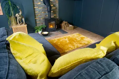 a living room with a couch with yellow pillows and a fireplace at Bird Nest - dine with the eagles Private Retreat in Carlisle
