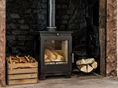 a black stove with a pile of wood at 2 Bed in Arlecdon 95126 in Arlecdon