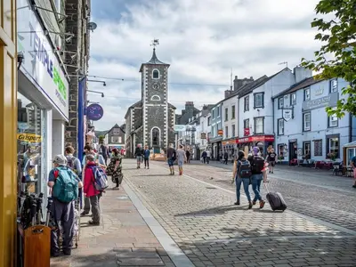 a group of people walking down a street with a clock tower at 3 Bed in Keswick oc-95032 in Keswick