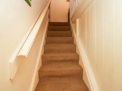 a stairway with brown carpet and white walls at Gardeners Cottage in Millom