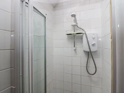 a bathroom with a shower with a glass door at Gardeners Cottage in Millom