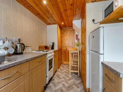 a kitchen with wooden cabinets and a white refrigerator at Carraig Dhubh North - Uk47125 in Whiting Bay