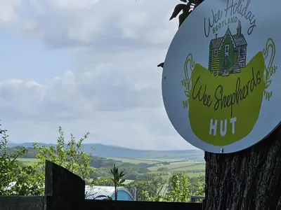 a sign on a tree with a house on it at Wee Shepherds Hut Maybole in Maybole