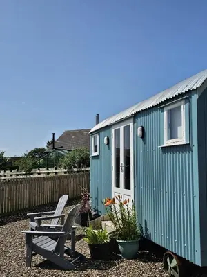 a green shed with a bench and a table at Wee Shepherds Hut Maybole in Maybole