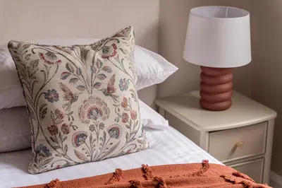 a pillow on a bed with a lamp on a night stand at Oakbank-Central Grasmere in Grasmere