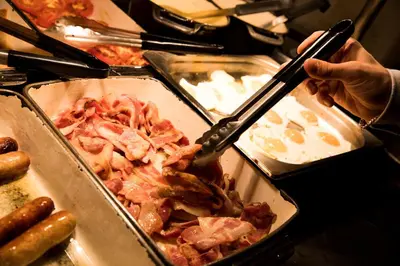a person holding a pair of tongs over a pan of food at Patterdale Hotel in Patterdale