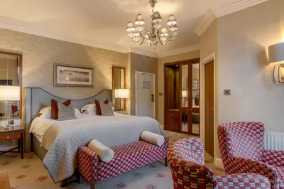 a bedroom with a bed and two chairs and a chandelier at The Inn On The Lake in Glenridding