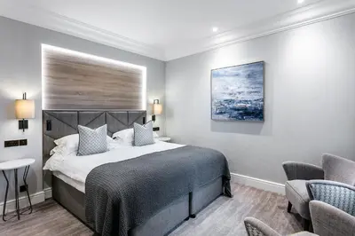 a bedroom with a large bed and two chairs at The Inn On The Lake in Glenridding