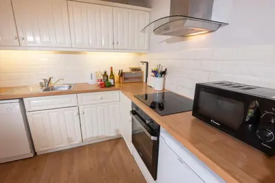 a kitchen with white cabinets and a black microwave at Myrtle Cottage in Chapel Stile