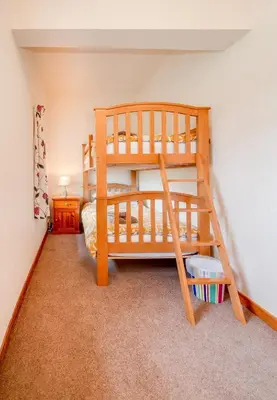 a bedroom with two bunk beds and a ladder at Courtyard Cottages Rose Cottage in Wigtown