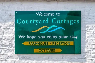 a sign on a wall that says welcome to couryardcolectales at Courtyard Cottages Rose Cottage in Wigtown