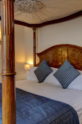 a bedroom with a bed with a wooden headboard and pillows at Crown & Mitre Hotel in Carlisle