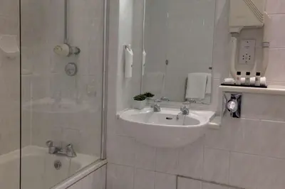 a white bathroom with a sink and a shower at Crown & Mitre Hotel in Carlisle