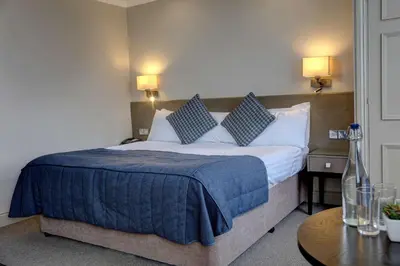 a hotel room with a bed with a blue blanket at Crown & Mitre Hotel in Carlisle