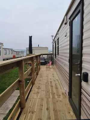 a large wooden deck next to a building at Static Caravan situated at Wigbay, Stranraer in Stranraer
