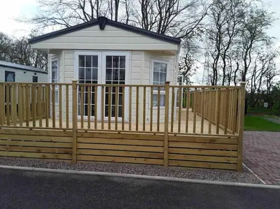 a wooden fence in front of a tiny house at Forestbrook - Cheerful two bedroom tiny house in Carlisle