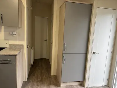 a kitchen with white cabinets and a white refrigerator at Forestbrook - Cheerful two bedroom tiny house in Carlisle
