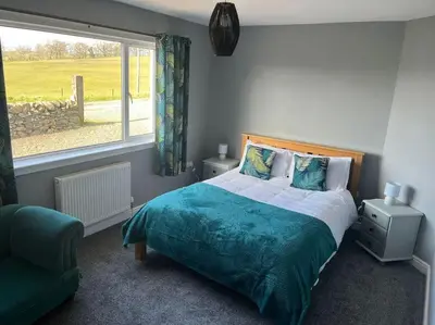 a bedroom with a large bed and a window at Barnbackle Cottage in Shawhead