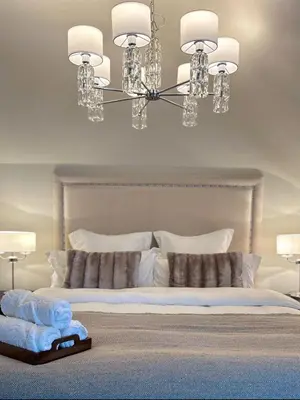 a bedroom with a white bed with a chandelier at Longbank Luxury Lets in Ayr