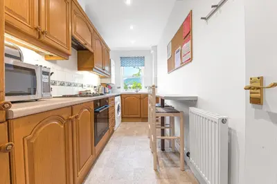 a kitchen with wooden cabinets and a ladder in it at The Hytte, 19 Greta Grove House in Keswick