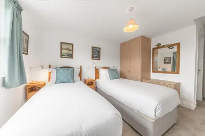 two twin beds in a room with a mirror at The Hytte, 19 Greta Grove House in Keswick