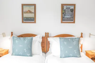 a bedroom with two beds with blue and white pillows at The Hytte, 19 Greta Grove House in Keswick