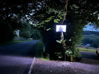a sign on a tree on the side of a road at Castle Glen Lodge in Dumfries