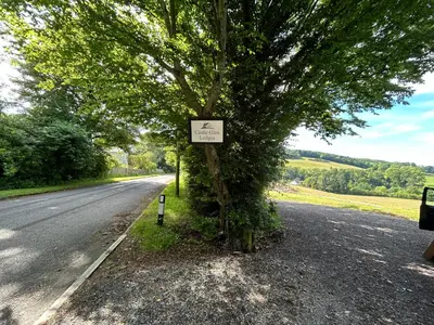 a tree on the side of a road with a sign on it at Castle Glen Lodge in Dumfries