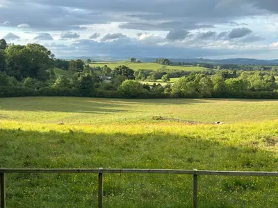 a field of green grass with a fence in the foreground at Castle Glen Lodge in Dumfries