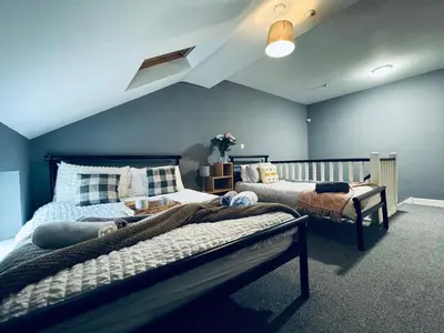 a bedroom with two beds and a blue wall at Queens Townhouse - 4 Bedrooms - Sleeps 9 in Whitehaven