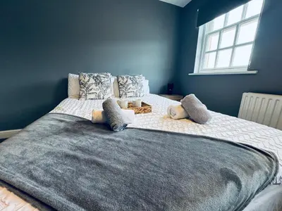 a large bed in a bedroom with a blue wall at Queens Townhouse - 4 Bedrooms - Sleeps 9 in Whitehaven