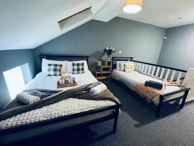 a bedroom with two beds and a blue wall at Queens Townhouse - 4 Bedrooms - Sleeps 9 in Whitehaven