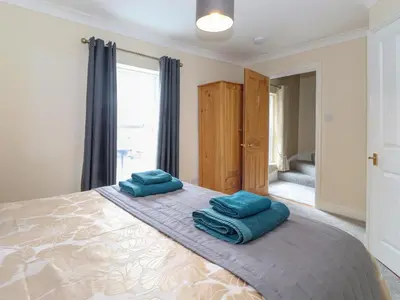 a bedroom with a large bed with blue pillows on it at Melbreak House 2 in Keswick
