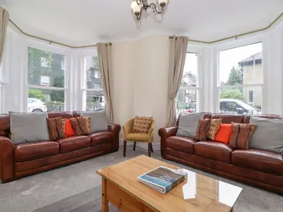 a living room with brown leather couches and a table at Melbreak House 2 in Keswick
